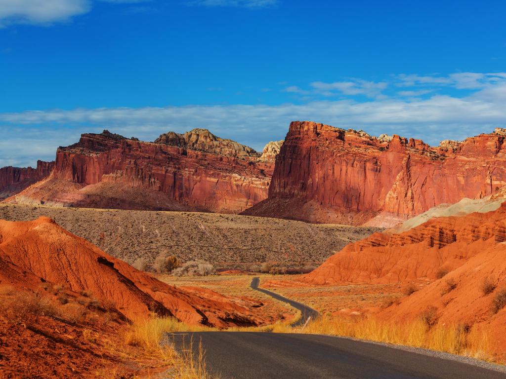Capitol Reef National Park, Utah, USA with a road leading to the orange formations of rocks and hoodoos taken on a clear sunny day.
