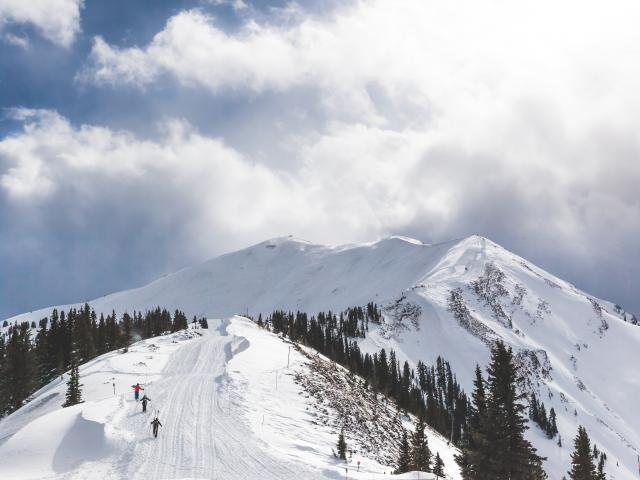A group of skiers hiking up to the Aspen Highlands Bowl
