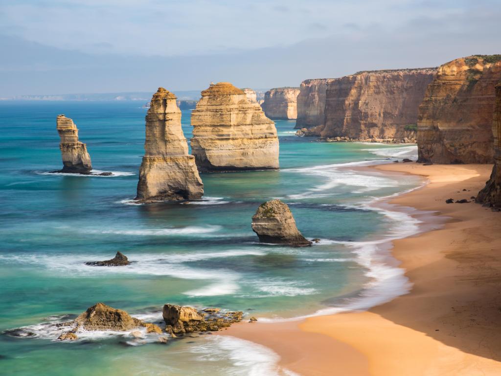 The 12 Apostles, Port Campbell, Victoria taken along the Great Ocean Road, with rock formations standing out of the water and cliffs with sand below.