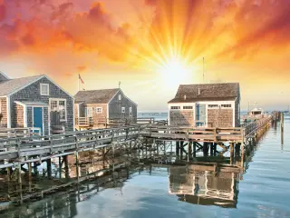 Wooden buildings on the port with a fiery sunset in the background