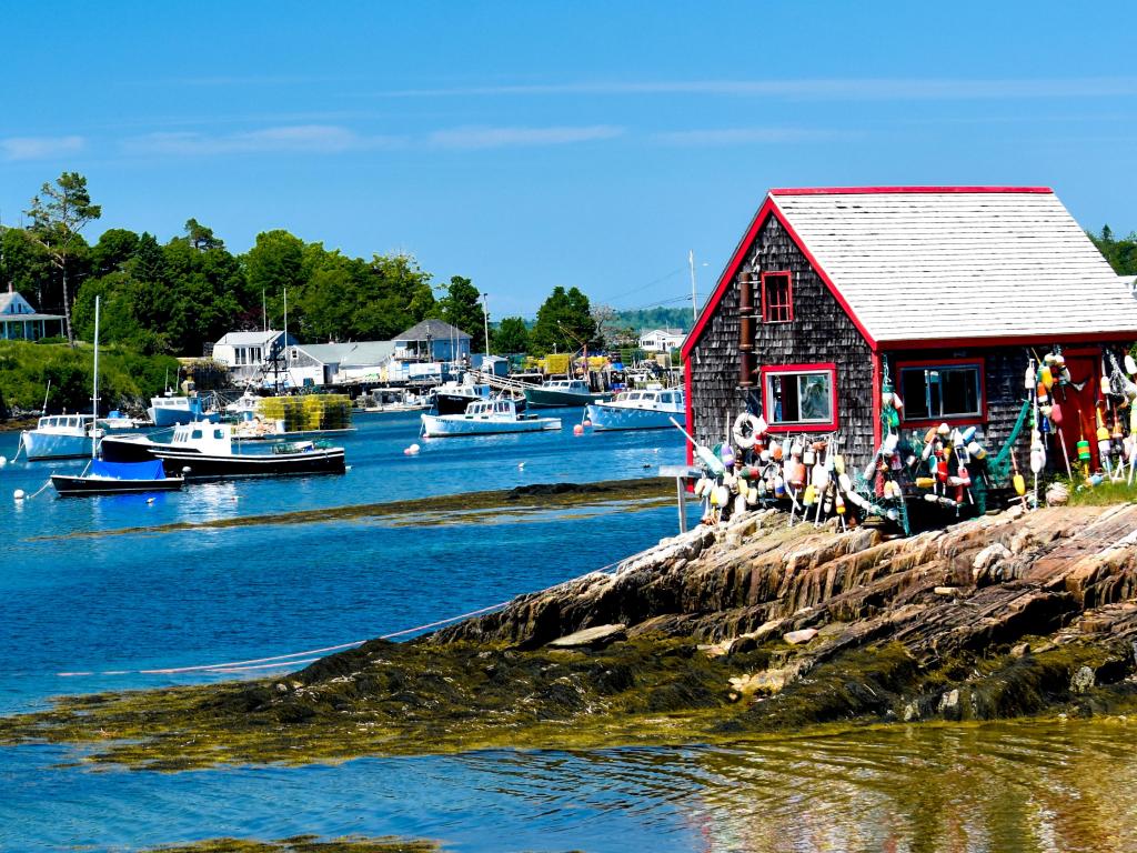 Boat House on Bailey's Island in Harpswell, Maine taken on a sunny day with boats in the distance. 