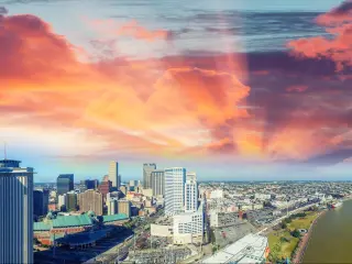 Aerial view of city sitting on riverbanks with vibrant pink sunset sky