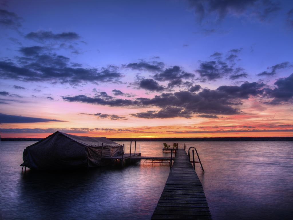 Lake Cayuga, Finger lakes region, New York State, USA with a beautiful fall sunrise on the shores of Lake Cayuga and a pier leading out to a deck with chairs for watching the fabulous sunrise.