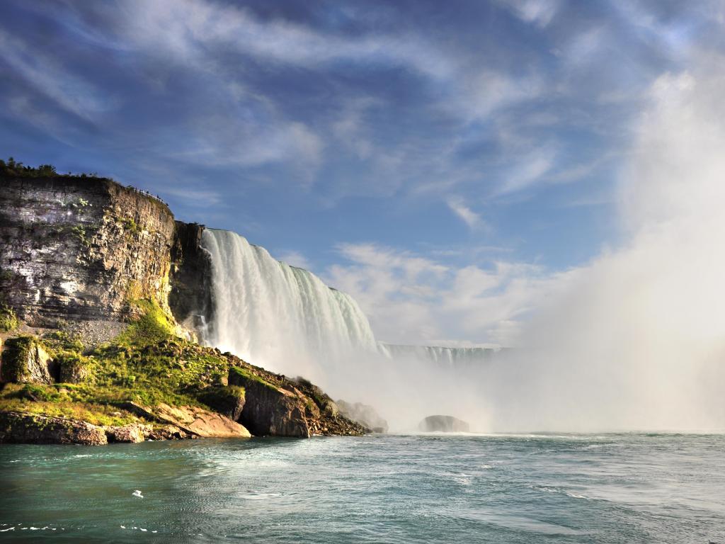 Niagara Falls, USA taken from a boat view with the waterfall in the background and lots of sea mist.