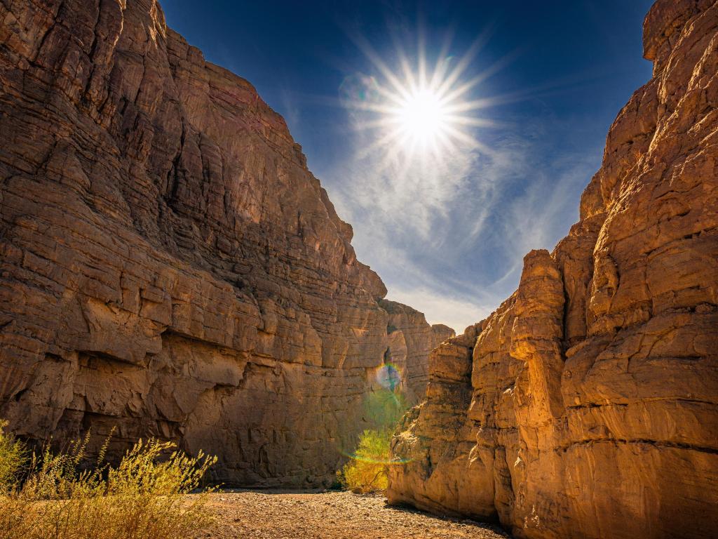 Ladder Canyon trail in Mecca, California, with tall cliffs either side and sun flare in between