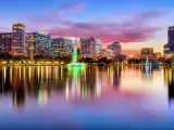 Orlando, Florida, USA downtown city skyline from Eola Park at night with the city skyline reflecting in the water in the foreground.