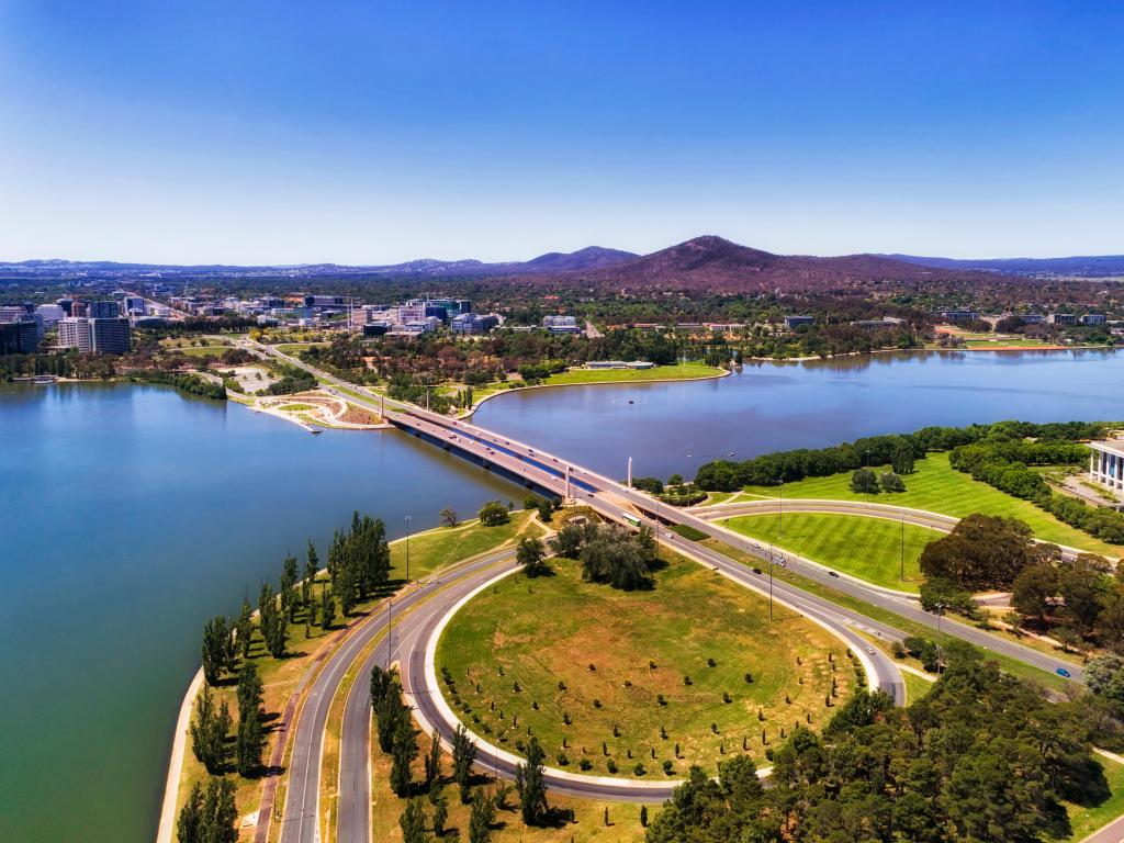 Canberra, Australia with a view of the commonwealth avenue and bridge over Burley Griffin lake in Canberra between city CBD and federal government capital hill triangle area with local streets, roads, parks and buildings.