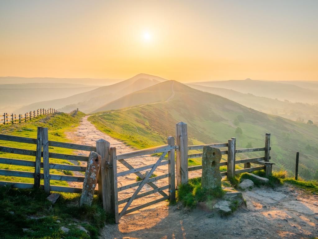 The Great Ridge in the Peak District, England taken at sunrise with a fence and path leading to hills in the distance.  