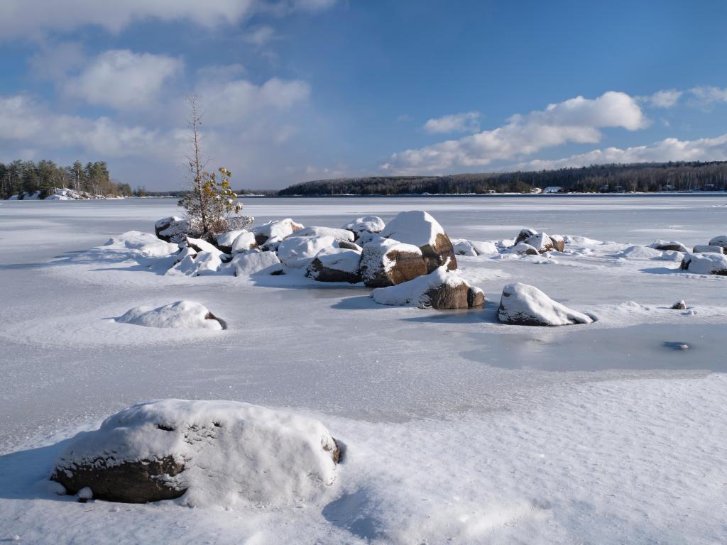A winter scene of large snow covered granite boulders surrounded by the ice as it forms in Lower Buckhorn Lake, in the Kawarthas, Ontario.