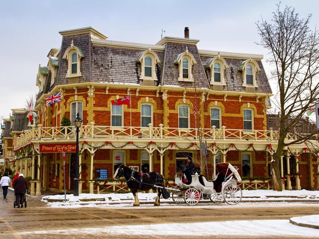 Historic Prince of Wales Hotel in Niagara On The Lake, Ontario, Canada in the snow with horse drawn carriage in the foreground