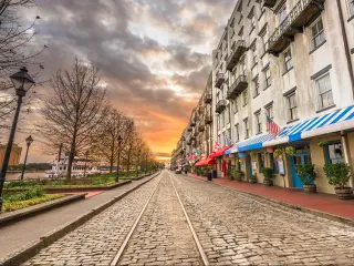 Savannah, Georgia, USA with bars and restaurants on River Street at dawn.