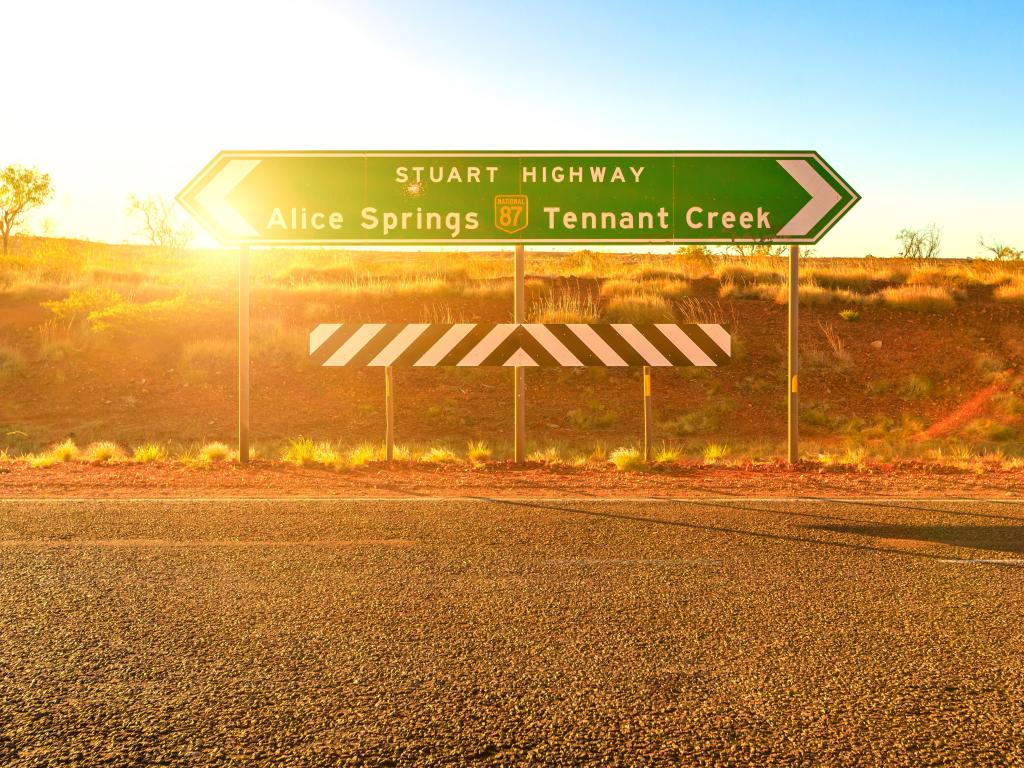 Sign on the Stuart Highway in Australia's Northern Territory showing the way to Alice Spings and Tennant Creek with sun behind