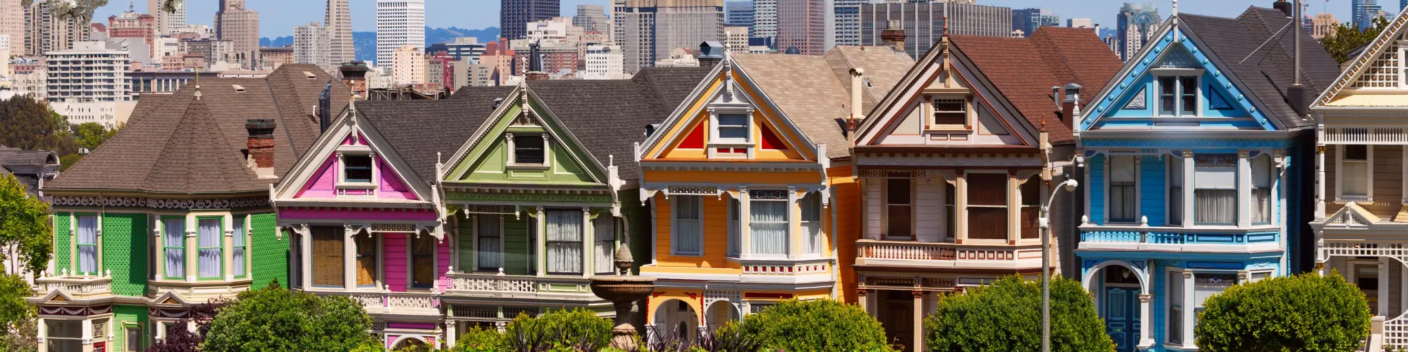 Painted Ladies, a group of famous colorful houses, on a spring day with blossoming trees in the foreground
