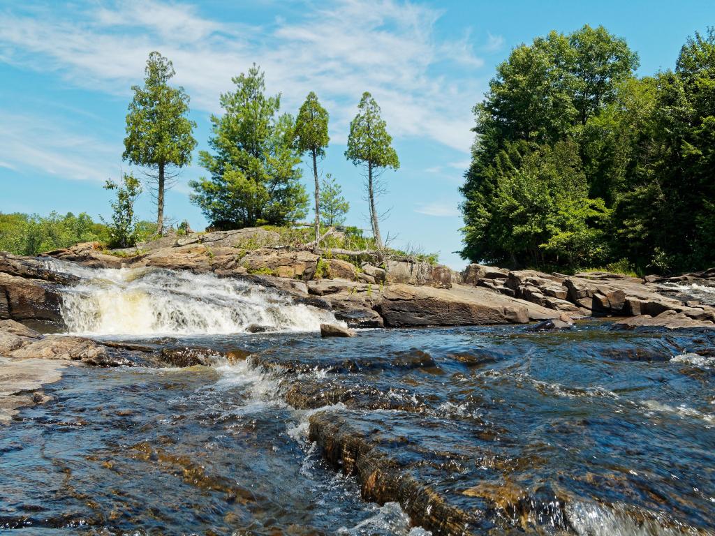 Batiscan River Park, Canada with a waterfall in the foreground, trees and rocks in the background and taken in a sunny day.