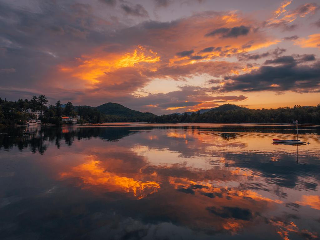 Lake Placid, New York, USA with a stunning sunrise taken at Mirror Lake, silhouette hills and trees in the far distance. 