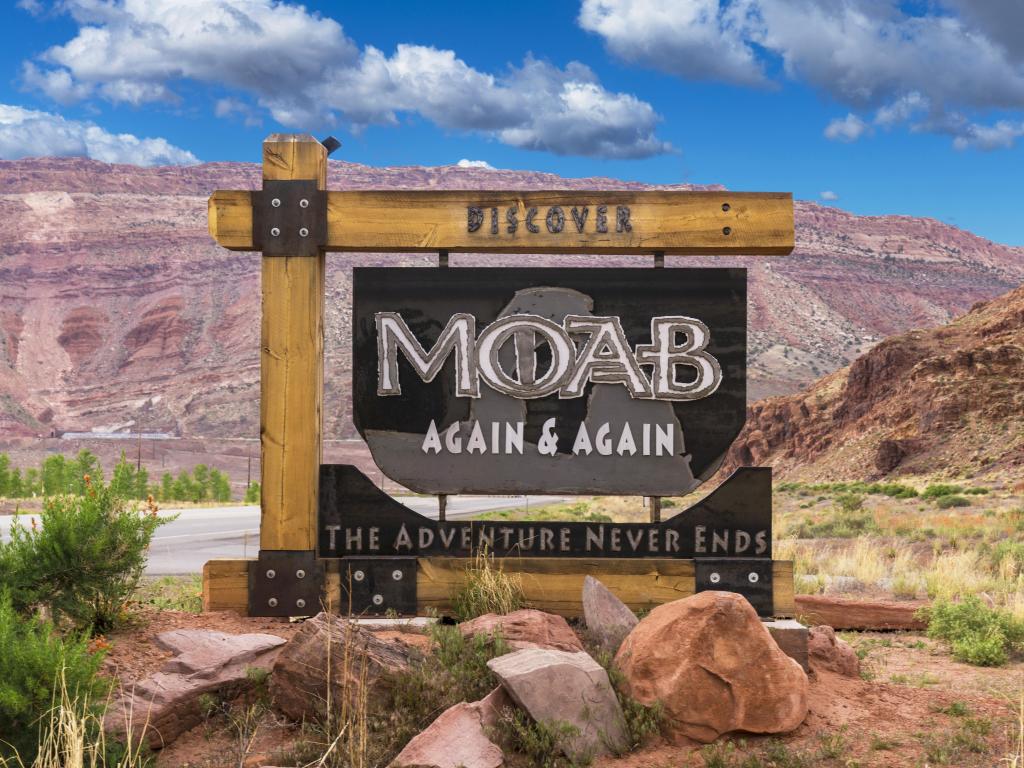 Sign at the entrance of Moab on a sunny day with mountains in the background