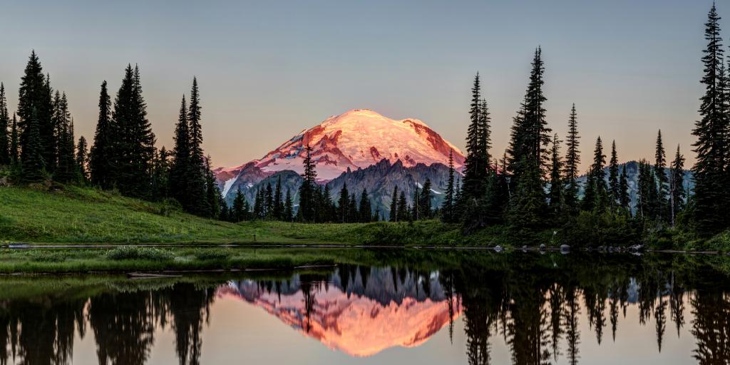 The snow-capped tip of Mount Rainier glows in the sunrise at Mt Rainier National Park