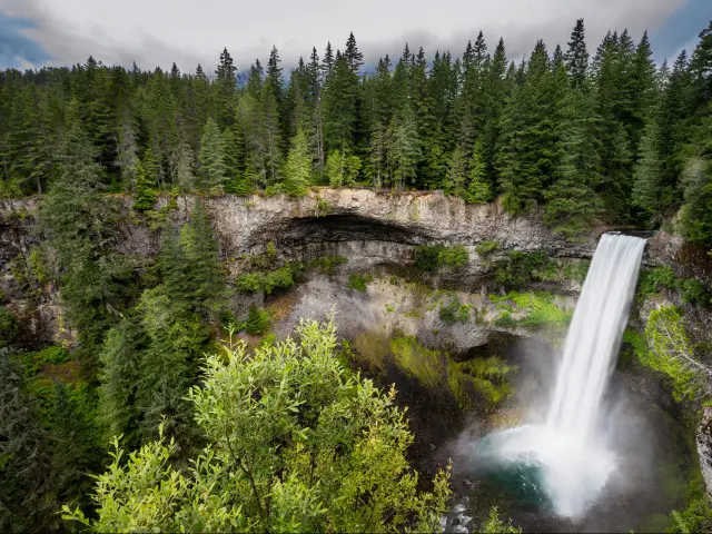 Brandywine Falls in Whistler, British Columbia, Canada taken from high looking down to the stunning waterfall surrounded by forests, stone and taken on a sunny day.