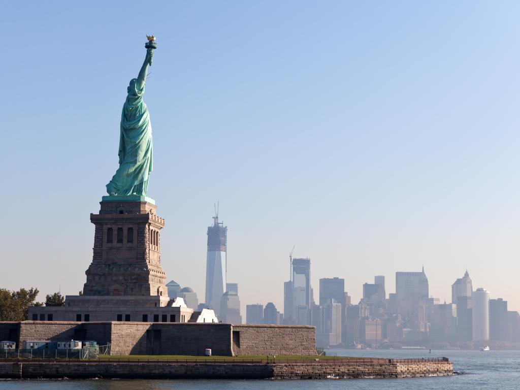 The Statue of Liberty free of tourists and New York City Downtown on sunny early morning