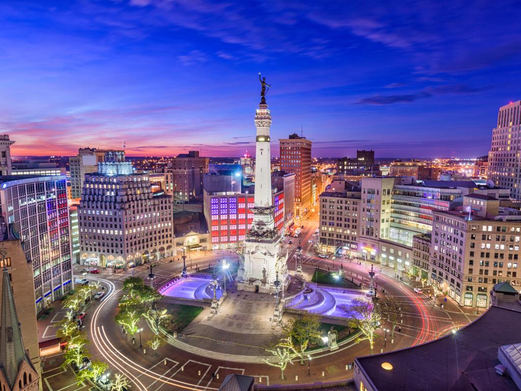 Indianapolis, Indiana, USA skyline over Monument Circle at night with the city lit up in bright colours.