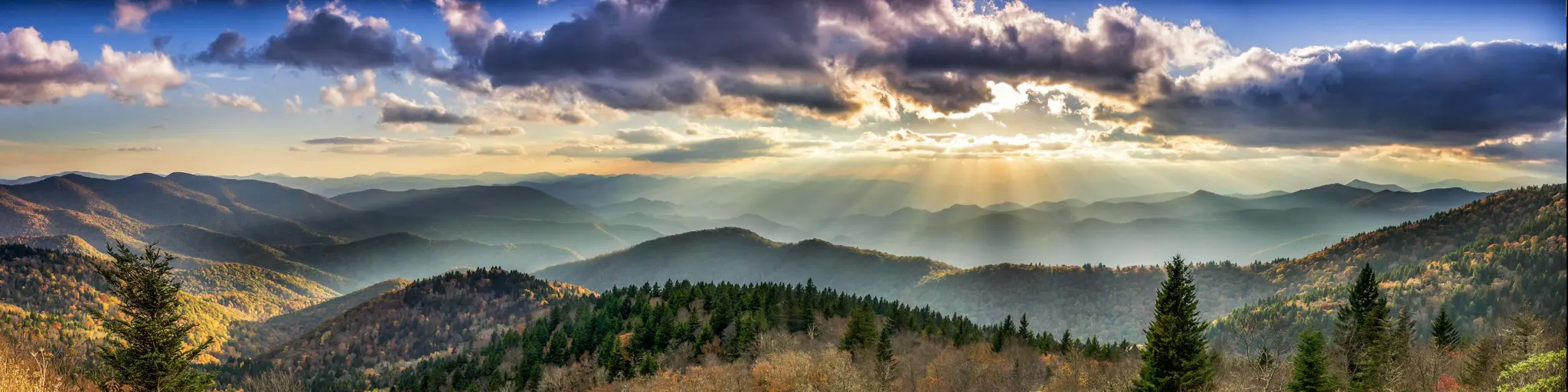 Panoramic view of tree covered mountains lit up with bright sun beams
