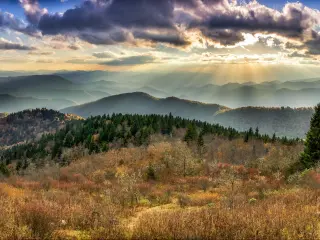Panoramic view of tree covered mountains lit up with bright sun beams