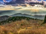Panoramic view of tree covered mountains lit up with bright sun beams