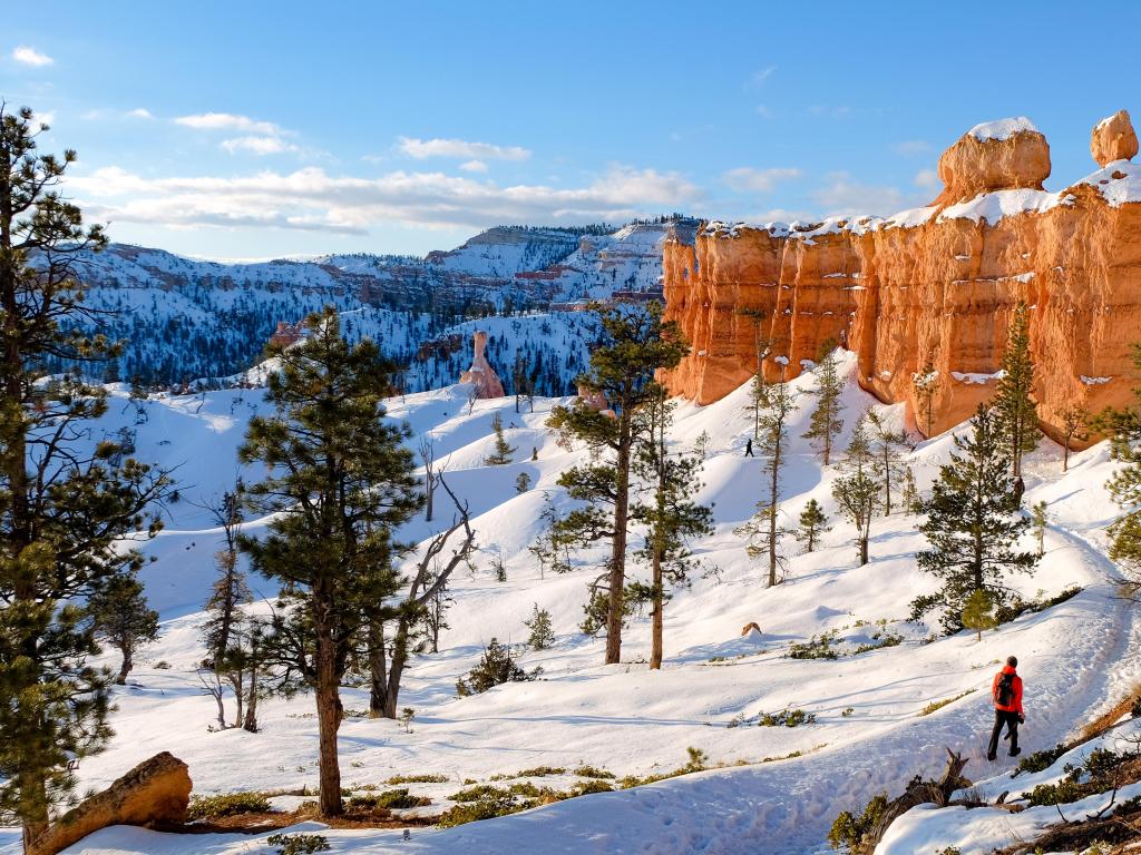 A hiker ventures along the snowy trails of Utah's Bryce Canyon National Park in winter.