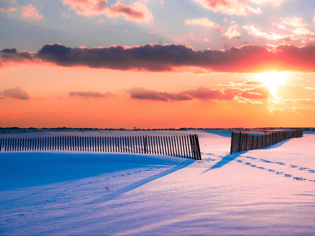 A snow covered beach in winter, with sun setting. Jones Beach State Park in Long Island NY