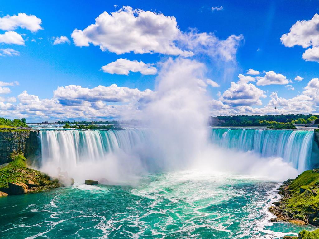 Niagara Falls, US/Canada taken on a sunny day and showing the great waterfall in the centre with water spray and the turquoise river below. 