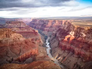 View over the South and North Rim part in Grand Canyon from the helicopter, USA. Dark clouds float in the sky.