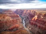 View over the South and North Rim part in Grand Canyon from the helicopter, USA. Dark clouds float in the sky.