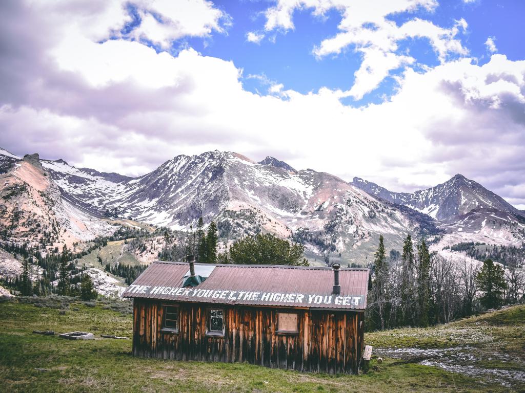 Ketchum, Idaho, USA with a pioneer cabin in the foreground and the Pioneer Mountains in the background covered in snow.