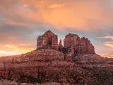 Sedona, Arizona, USA with a colorful sunrise over Sedona's Cathedral Rock landmark in the distance.