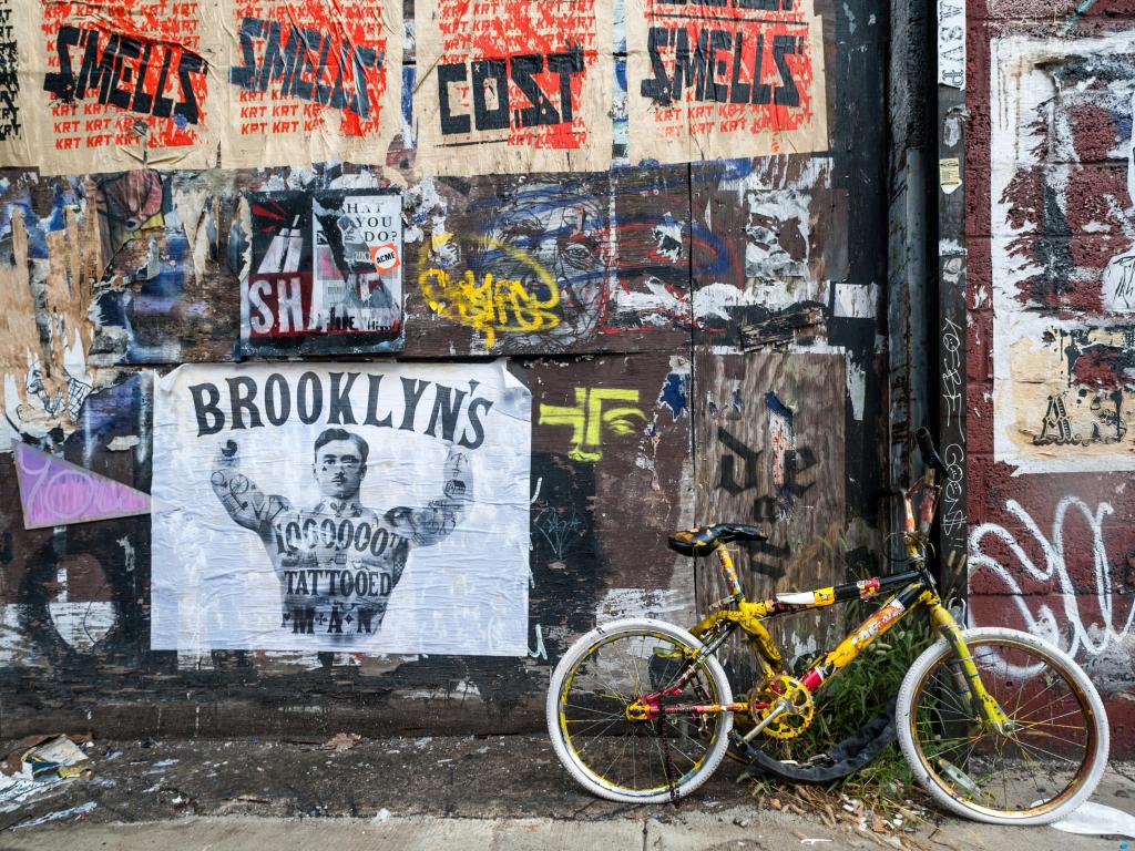 Bicycle parked in front of flyposting and graffiti covered wall in west Williamsburg, Brooklyn
