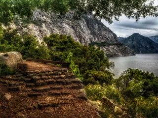 A picturesque foot bridge crossing along the Wapama Falls Trail, as storm clouds brew and the footbridge is lit in a beautiful brown