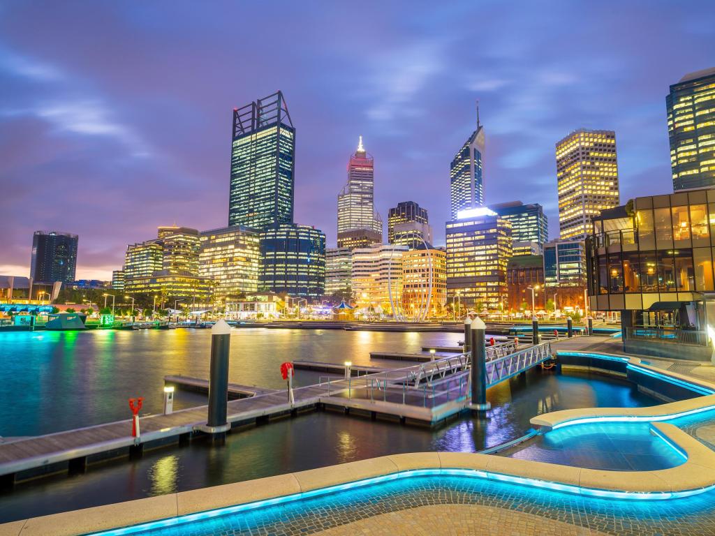 High rise buildings by the waterfront in Perth, with pier, waterfront and buildings illuminated at sunset