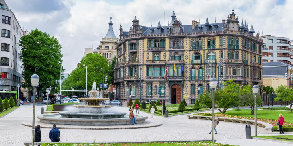 People walk around the fountain in the middle of Plaza Moyua in Bilbao