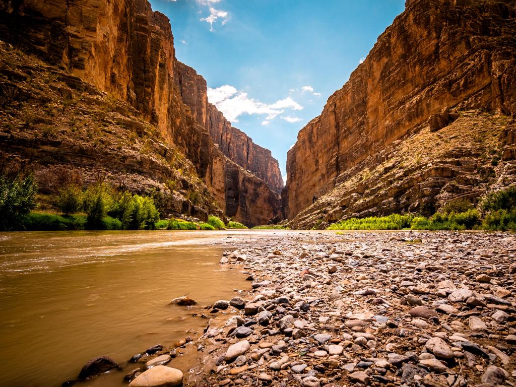 Santa Elena Canyon in Big Bend National Park, towering under the azure sky, is majestically straddled by the murky Rio Grande River, acting as the border with Mexico on one side and the USA on the other.