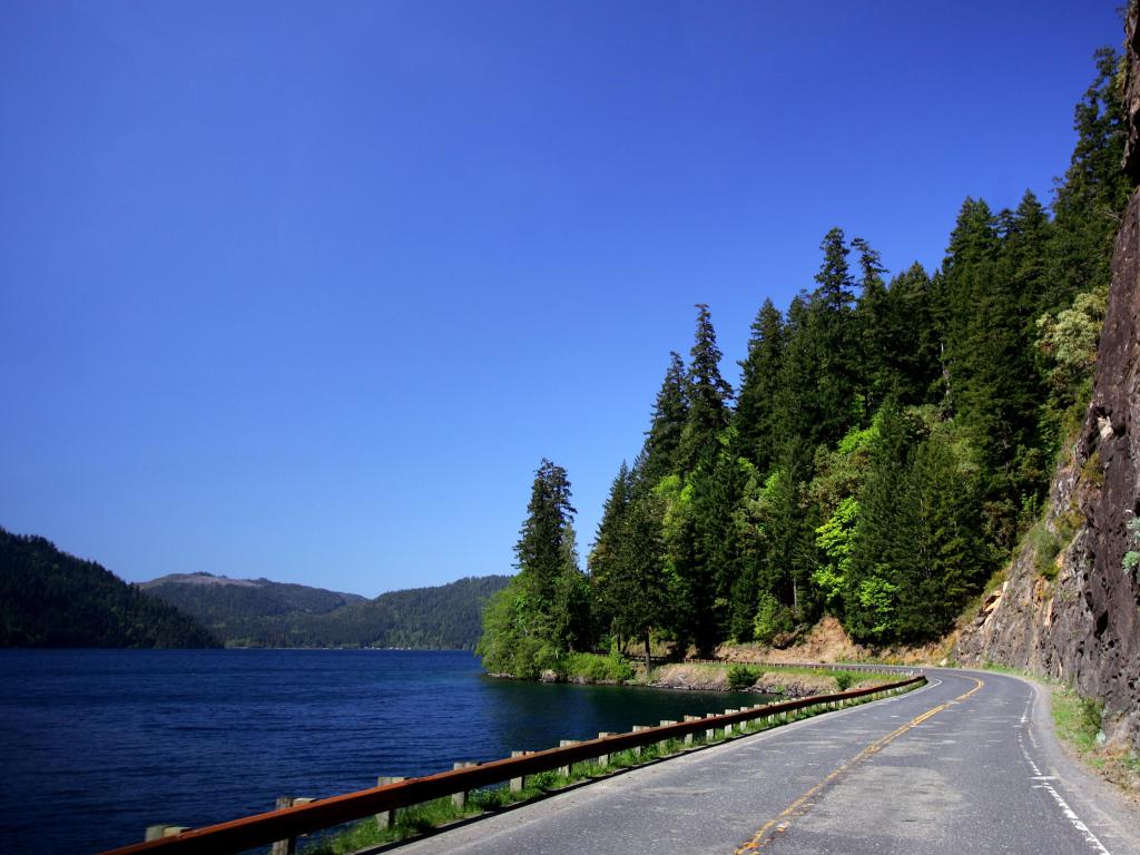 Winding Olympic Peninsula highway, surrounded by rocks and forests one side and water alongside the other