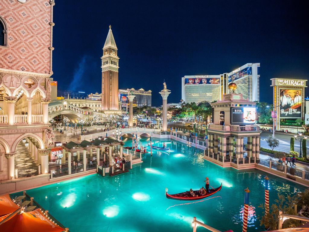 The pool at the Venetian Hotel lit up at night with the Strip in the background