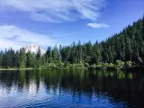 Pine forests surrounding Mirror Lake, clearly reflected in the water, and clear blue skies overhead