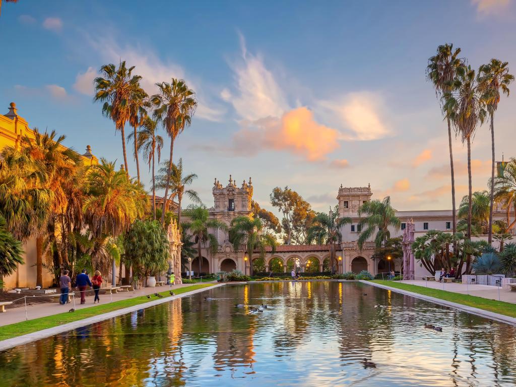 Balboa public park, San Diego at sunset, with water glistening in the foreground and palm trees 