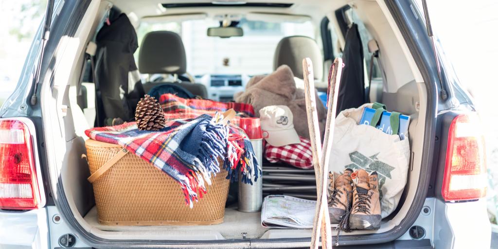 Picnic basket, blanket, clothes and bags packed into the boot of a car