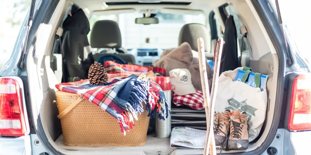 Picnic basket, blanket, clothes and bags packed into the boot of a car