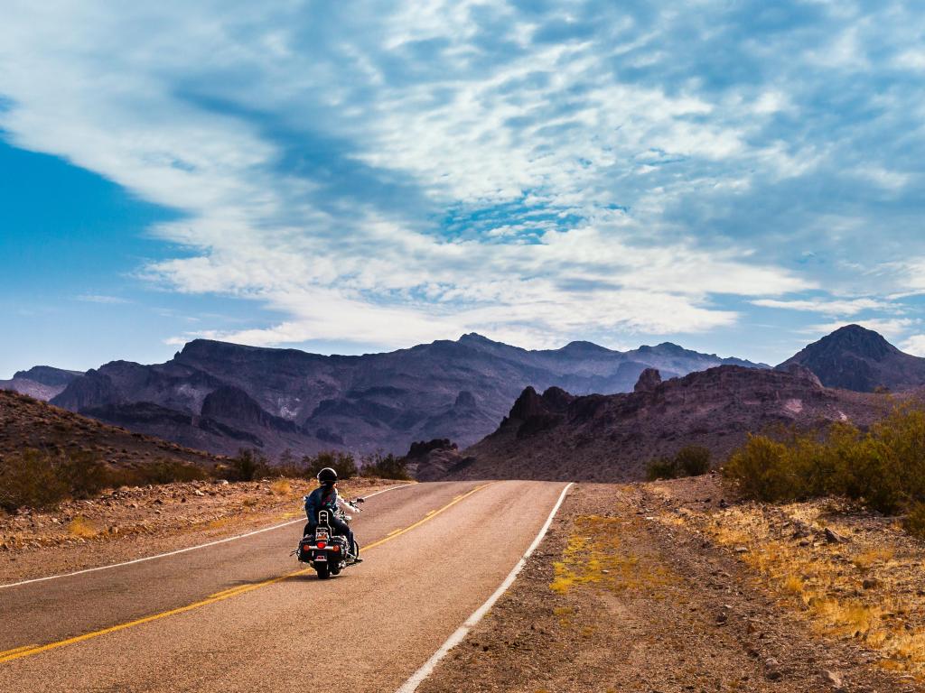 A lone biker rides down old Route 66 through Arizona, beneath a blue sky