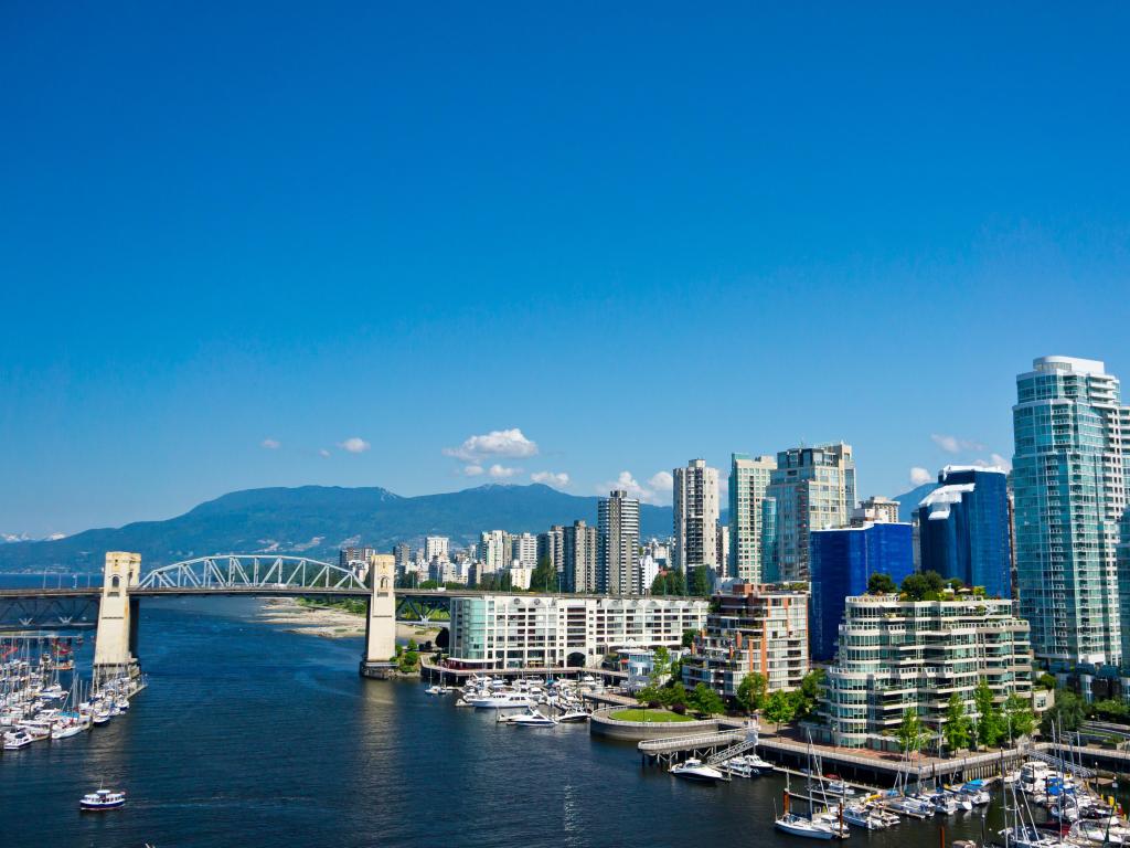 Vancouver, British Columbia, Canada with a beautiful view of the city in the background and the bridge crossing the water, plus mountains in the distance on a sunny clear day.