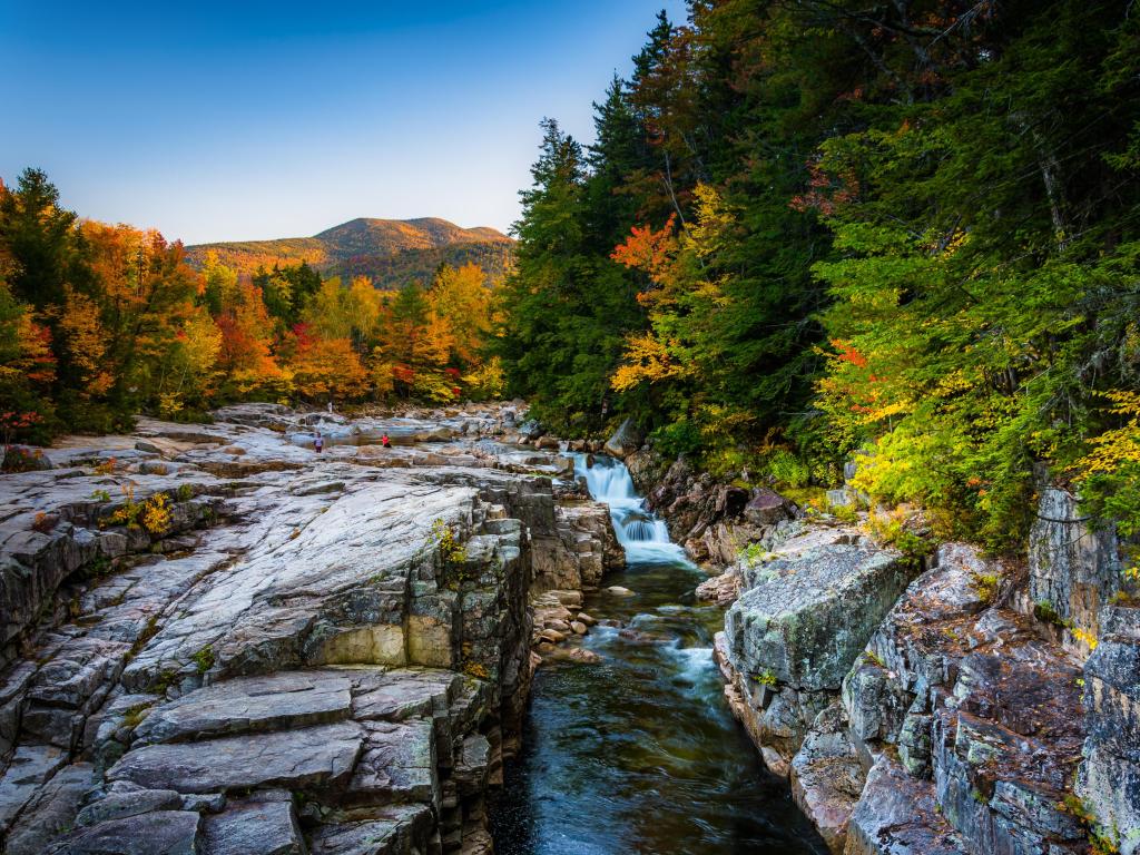 White Mountain National Forest, New Hampshire, USA with a fall evening view of Rocky Gorge, on the Kancamagus Highway with rocks, river and mountains in the distance.