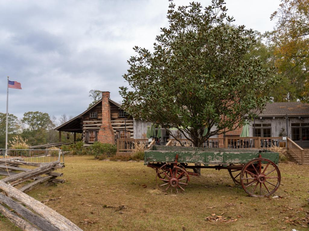 Log cabin at French Camp, Mississippi on the Natchez Trace Parkway, with a historic wooden cart outside on its lawn