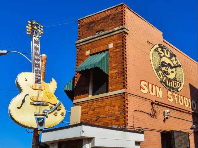 Large guitar outside brick building in front of blue sky